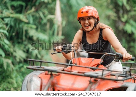 asian woman riding the atv happily through the difficult terrain at amusement park