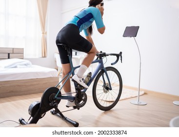 Asian Woman Riding A Bike Online Trainer In The Bedroom