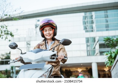 Asian Woman Riding A Motorcycle Wearing A Helmet