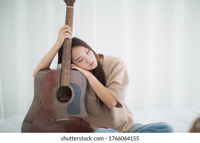 Asian Woman Sad Hug Guitar In Home