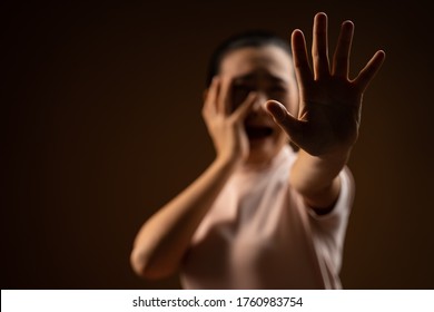 Asian Woman Scared Screaming Covering Face By Her Hands Standing Isolated On Beige Background. Low Key.