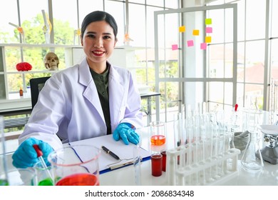 Asian Woman Scientist And Biology Researcher Working With Glass Tube And Beaker Of Chemistry Experiment In Scientific Lab Of Investigation Equipment And Microscope.