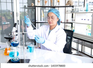 Asian Woman Scientist, Researcher, Technician, Or Student Conducted Research Or Experiment By Using Microscope Which Is Scientific Equipment In Medical, Chemistry Or  Biology Laboratory