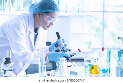 Asian Woman Scientist, Researcher, Technician, Or Student Conducted Research Or Experiment By Using Microscope Which Is Scientific Equipment In Medical, Chemistry Or  Biology Laboratory