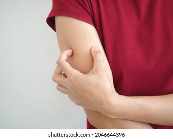 Asian woman scratching arm from having itching. cause of itchy skin include insect bites, dermatitis, or dry skin. health care concept. closeup photo, blurred.