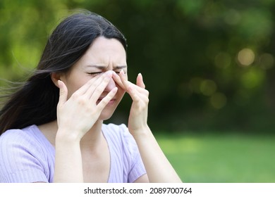 Asian woman scratching itchy eyes in a park in summer