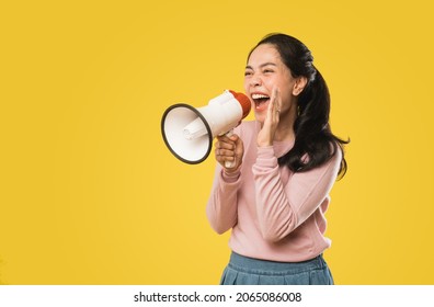 Asian woman screaming while holding megaphone with two hands making announcement