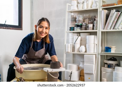 Asian woman sculptor artist showing handicraft ceramic pottery in her hand at ceramic studio. Female craftsman sculpture pottery on pottery wheel. Small business owner art and craft product concept.de - Powered by Shutterstock