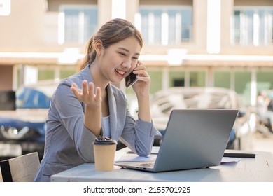 Asian Woman, Self-employed, Focusing On Mobile Phone With The Laptop. Financial Analysis, Graphs, Accounts, Charts, Online Marketing Plans, Working Concepts Based On Coffee Shops Outside The Home.