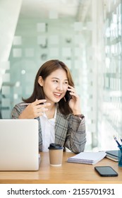 Asian Woman, Self-employed, Focusing On Mobile Phone With The Laptop. Financial Analysis, Graphs, Accounts, Charts, Online Marketing Plans, Working Concepts Based On Coffee Shops Outside The Home.