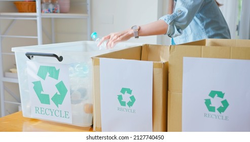 Asian woman is separating trash and sort waste in garbage box for recycling at home - Shutterstock ID 2127740450