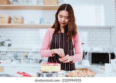 Asian woman as she indulges in her passion for cake making and decoration in the comfort of her lifestyle kitchen, the joy of pursuing one's hobbies