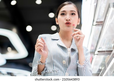 Asian Woman Shopping In The Store Cosmetics,happiness Smiling Asian Female Make Funny Face To Camera While Hand Use Lipstic Taster At Cosmetic Store In Department Mall