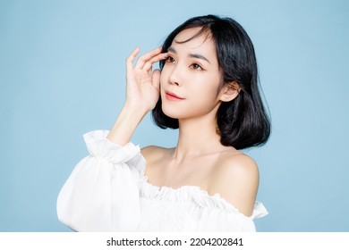 Asian Woman Short Hair With Perfect Clean Fresh Skin. Cute Female Model With Natural Makeup And Sparkling Eyes On Blue Isolated Background. Facial Treatment, Cosmetology, Beauty Concept.