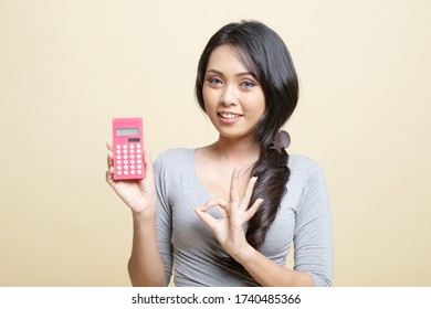 Asian woman show OK with calculator   on beige background - Shutterstock ID 1740485366