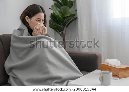 Asian woman sick with fever, runny nose and cough at home during the COVID-19 outbreak.