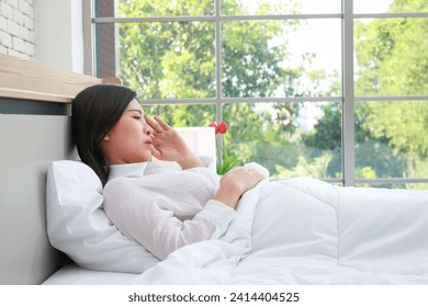 Asian woman is sick and has a headache. She is resting in bed. Health concept. Flu caused by a virus - Powered by Shutterstock