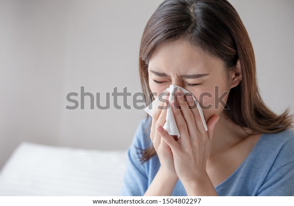 asian woman sick and sneeze with tissue paper in\
the bedroom