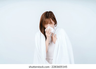 Asian woman sick and sneezing with tissue paper in bedroom - Powered by Shutterstock