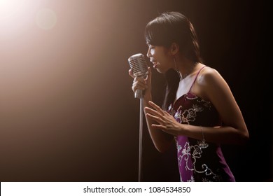 Asian Woman Singer Holding A Microphone Singing.