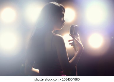 Asian woman singer holding a microphone singing. - Powered by Shutterstock