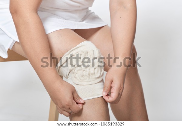 asian\
woman sit wearing a knee support for healing\
injury