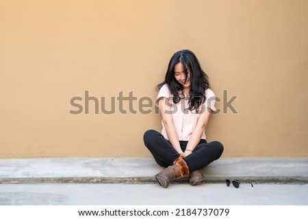 The Asian woman is sitting, crying and smiling alone at the same time on the rooftop of the building. This is not a good day for her.