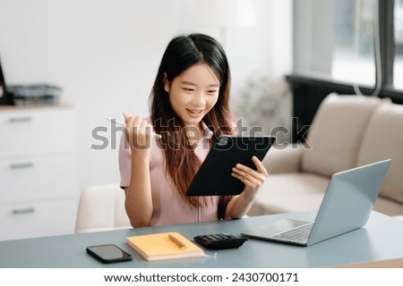 Asian woman sitting at a desk using a laptop computer Navigating Finance and Marketing with Technology in office