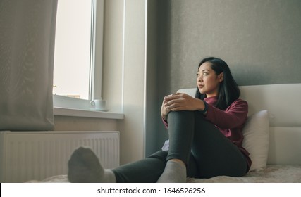 Asian Woman Is Sitting On The Bed Looking Out To The Windows And Thinking Or Missing Of Someone.