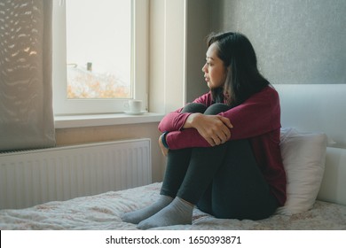 Asian Woman Is Sitting On The Bed Looking Out To The Windows And Thinking Or Missing Of Someone.