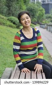 Asian Woman Sitting On Bench,outdoors.