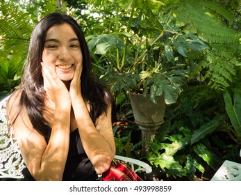 Asian woman sitting on chair in the garden, black hair, black vest, portrait, fern background, holiday, have a big smile - Shutterstock ID 493998859