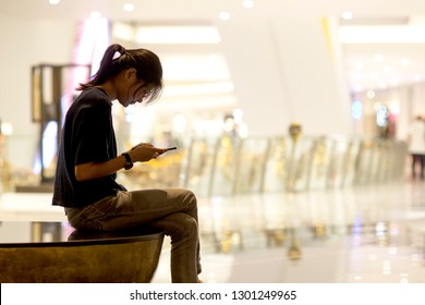 Asian Woman Sitting On The Phone With A Still Motion Without Being Interested In The Environment Playing Online Games, Nomophobia, Shopping On Line