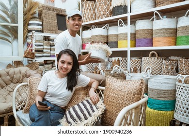 Asian Woman Sitting On The Sofa Holding Cellphones And Asian Man Holding Basket Crafts In The Craft Gallery