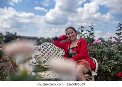 Asian Woman Sitting On White Iron Bench In Park