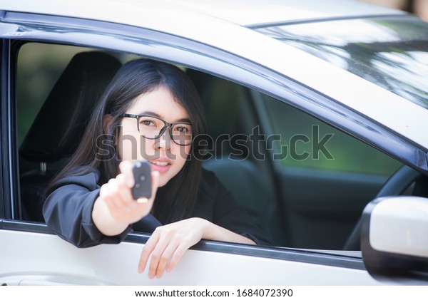 Asian woman sitting in a private car shows the keys\
in her hand.Selected\
focus