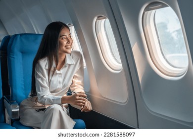 Asian woman sitting in a seat in airplane and looking out the window going on a trip vacation travel concept - Shutterstock ID 2281588097