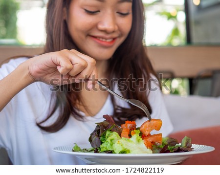 An Asian woman sitting at a table eating salmon salad for good health. diet and Clean food