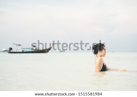 Asian woman sitting in water at the beach.