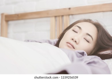 Asian woman sleep on  white pillow on bed in bedroom in holiday.happy relax time.color tone