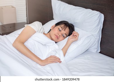 Asiatische Frau schläft auf weißem Bett zu Hause