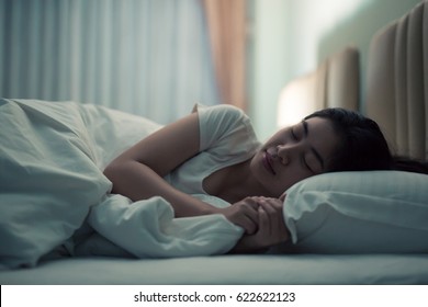 Asian Woman Sleeping In A Bed In A Dark Bedroom