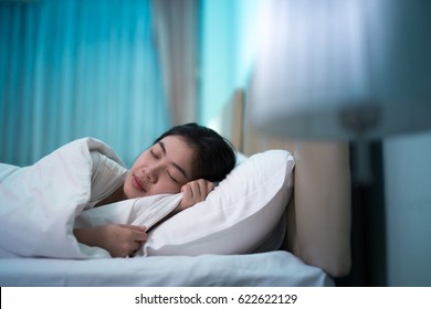 Asian Woman Sleeping In A Bed In A Dark Bedroom