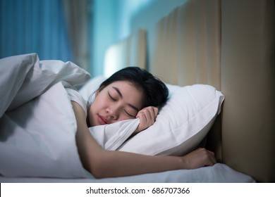 Asian Woman Sleeping In A Bed In A Dark Bedroom