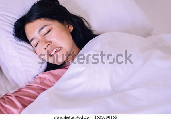 Asian woman sleeping and grinding teeth in\
bedroom,Female tiredness and\
stress