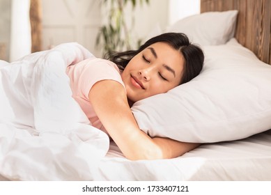 Asian Woman Sleeping Lying In Bed At Home Hugging Pillow On Weekend Morning. Healthy Sleep Concept