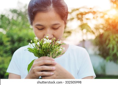 Asian Woman Smelling Flowers In Garden.

