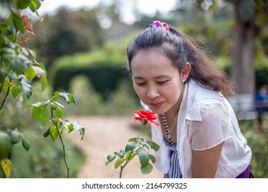 Asian Woman Smelling Flowers In The Park