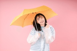 Femme Asiatique Souriante Et Fait Un Petit Coeur Avec Un Manteau Imperméable Et Tenant Un Parapluie Sur Fond Rose