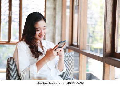 Asian Woman Smile With Mobile Phone Relaxing In Cafe